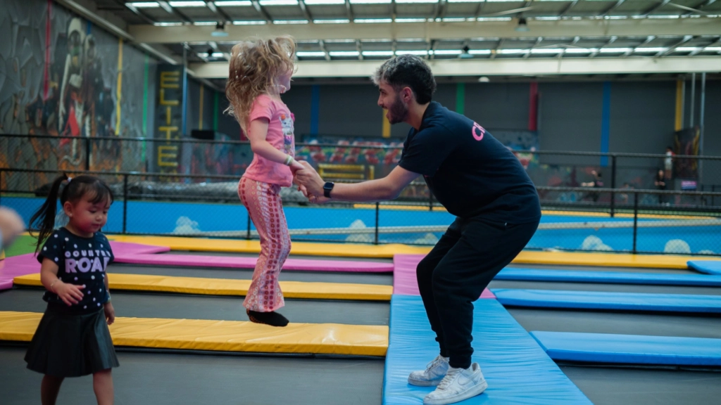 A staff member helping a young child jump on the trampolines at airborn